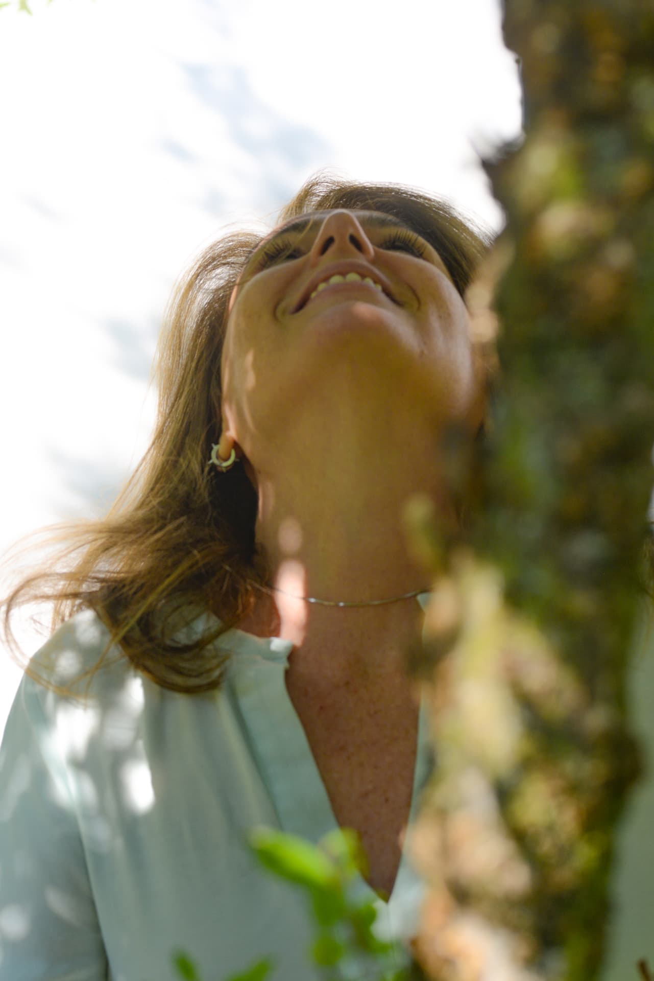 Fah Maioli looking up into the light through the leaves of a tree